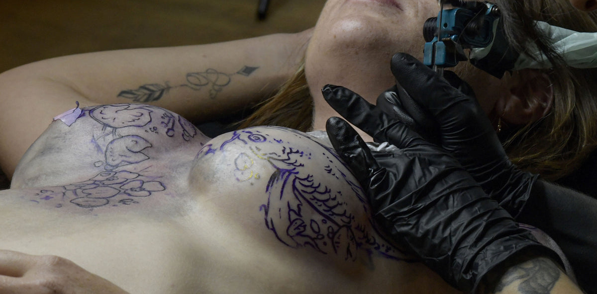 Une femme se faison tatoué la poitrine suite à un cancer du sein lors de l'évènement Rose tattoo organisé par Soeurs d'encre.